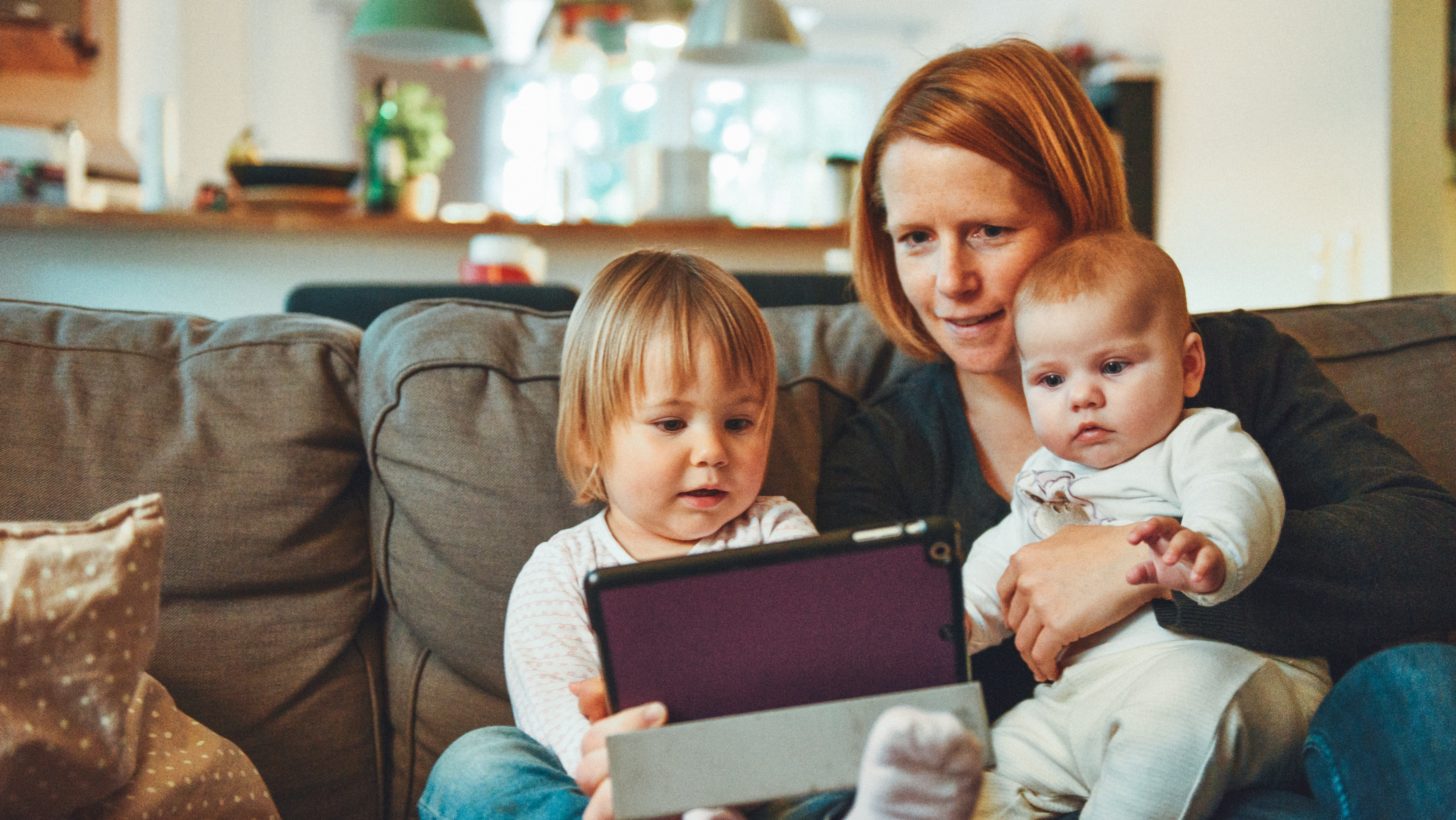 mother uses tablet with young children at home